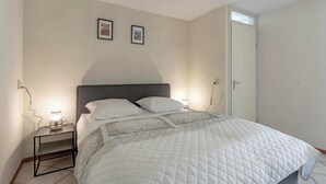 Une chambre à coucher avec un lit, deux tables de chevet, une commode et une porte.