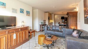 Un salon avec un téléviseur, un meuble en bois, un canapé et une table basse.