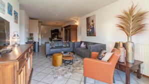 Un salon comprenant un canapé, des fauteuils, une table basse et un vase décoratif.