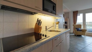 A modern kitchen with a microwave, sink, and knife block. - Wijde Blick 206 Apartment in Callanstoog (Callantsoog)
