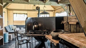 Una cucina rustica con un grande stufa, tavoli in legno e un'area salotto accogliente con cuscini.