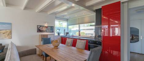 Une cuisine moderne avec une table en bois, des placards rouges et une vue sur la ville.