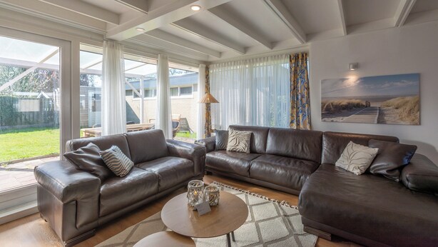 A spacious living room with a large brown leather sofa set, a coffee table, and a painting on the wall. - Modern Home Near Beach (Sint Maartensvlotbrug)