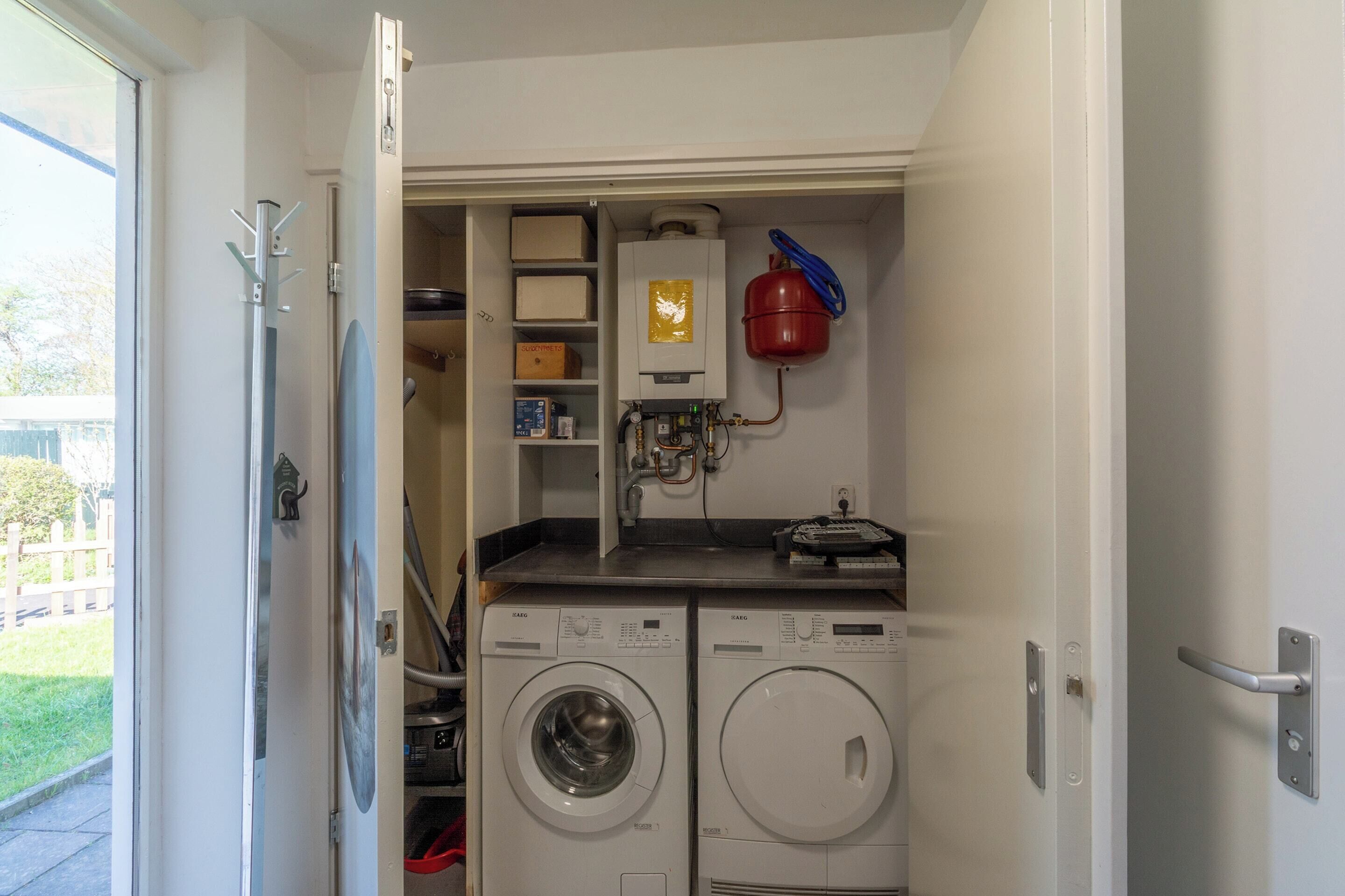 A laundry room with two washing machines, a water heater, and a fire extinguisher.