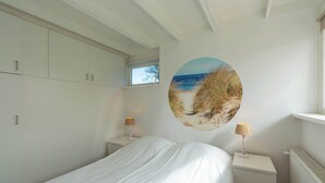 A bedroom with a bed, nightstands, a window, and a beach mural on the wall. - Modern Home Near Beach (Sint Maartensvlotbrug)