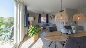 Un salon moderne avec un balcon, une table ronde en bois et un canapé.