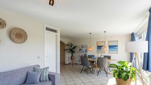 Un salon moderne comprenant un canapé, un coin repas et une grande fenêtre avec des rideaux.