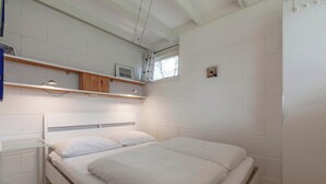 A bedroom with a single bed, white walls, and a window with a curtain. - Wildrijk 83 Holiday Home Near Beach (Sint Maartensvlotbrug)