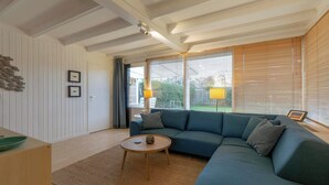 A modern living room with a sectional sofa, a round coffee table, and a wooden floor. - Wildrijk 83 Holiday Home Near Beach (Sint Maartensvlotbrug)
