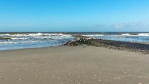 A beach with footprints leading to the water, a rocky area, and a clear sky. - Wijde Blick 310 Apartment Near Callanstoog Beach (Callantsoog)