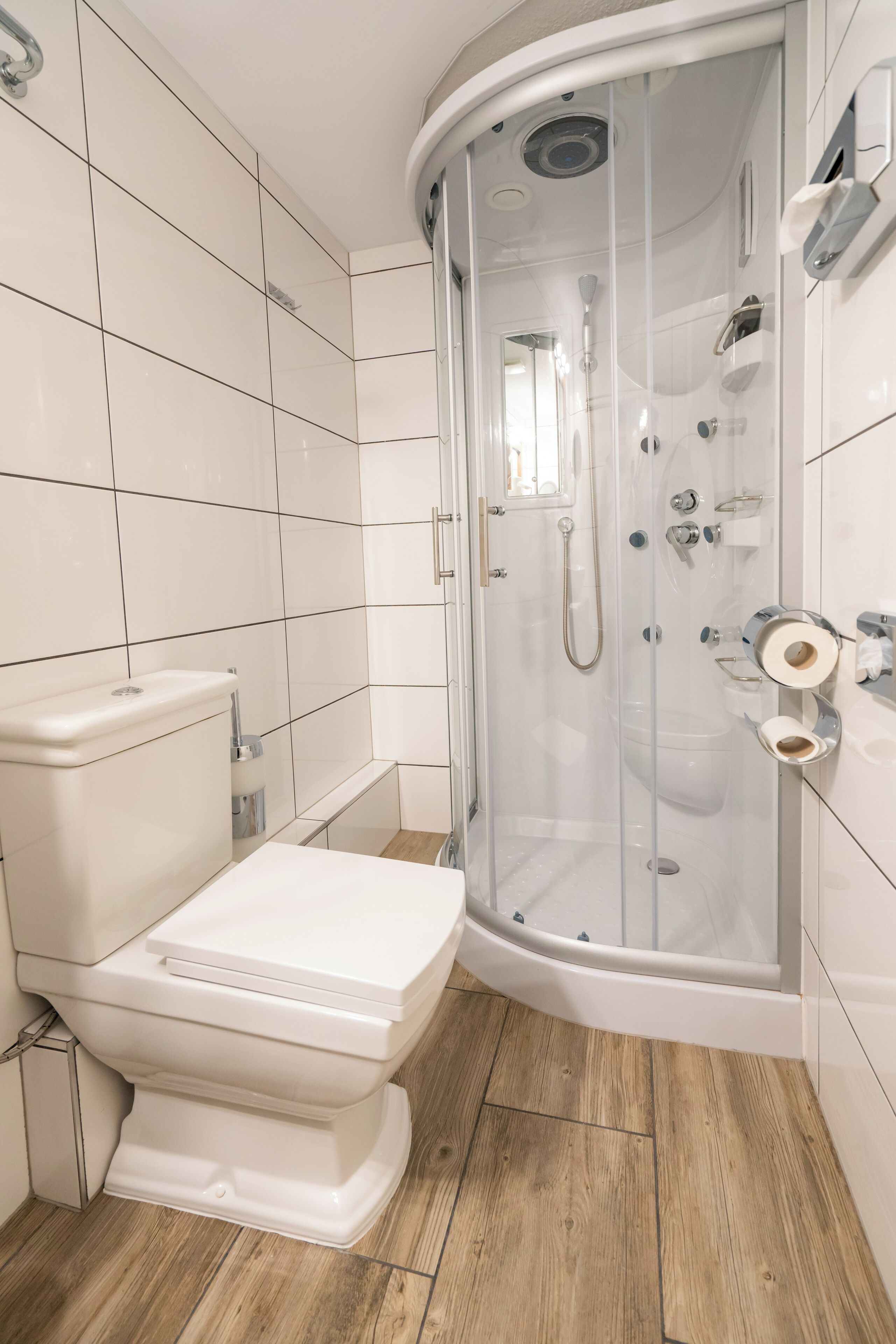 A modern bathroom with a toilet, shower enclosure, and tiled walls.