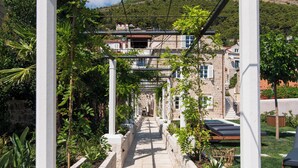 A pathway leading to a building with stone walls and a garden.