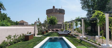 A swimming pool with lounge chairs and a garden area.