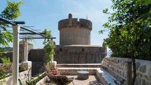 A stone tower with a circular top, surrounded by outdoor seating and greenery.