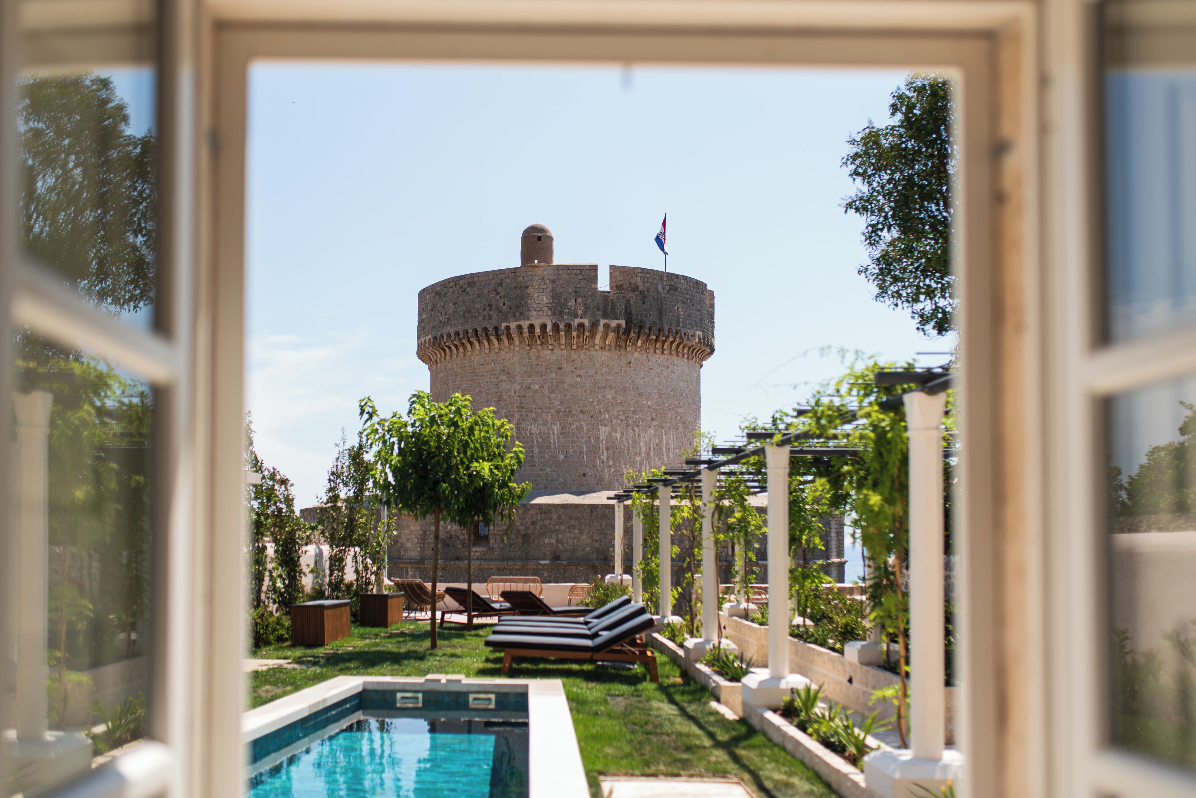 On peut voir une structure ressemblant à un château, avec un drapeau, une piscine et des chaises longues.