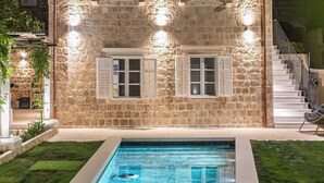 A stone building with a swimming pool, a staircase, and a balcony.