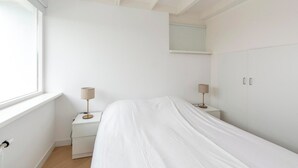 A bedroom with a bed, two bedside tables with lamps, a wardrobe, and a window. - Bungalow Near Sint Maartenszee Beach (Sint Maartensvlotbrug)