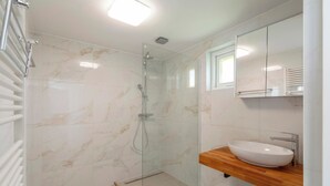 A modern bathroom with a glass-enclosed shower, a wooden vanity with a white sink, and a large mirror above the sink. - Bungalow Near Sint Maartenszee Beach (Sint Maartensvlotbrug)