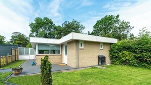 A modern two-story house with a flat roof, large windows, and a small front porch. - Bungalow Near Sint Maartenszee Beach (Sint Maartensvlotbrug)