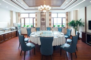 A dining area with a round table, chairs, and a chandelier. - Longtang Hotel (Harbin)