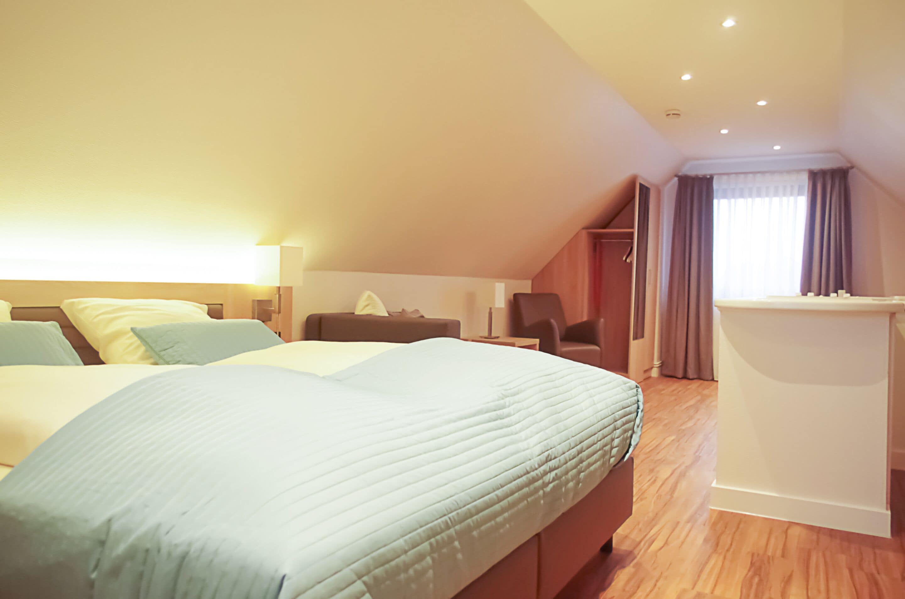A hotel room with a large bed, a desk, and a chair.