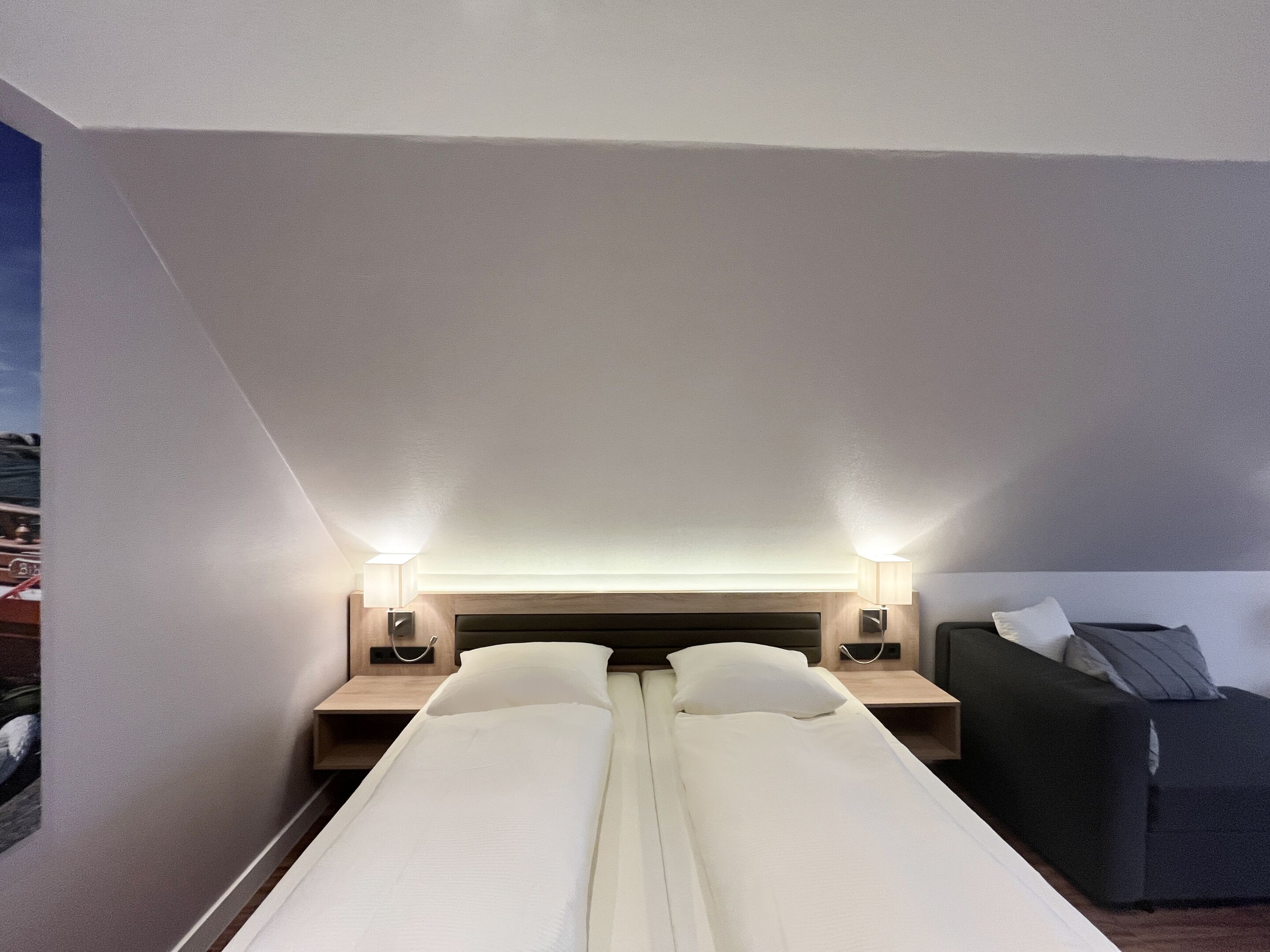 A hotel room with a bed, bedside tables, and a couch.