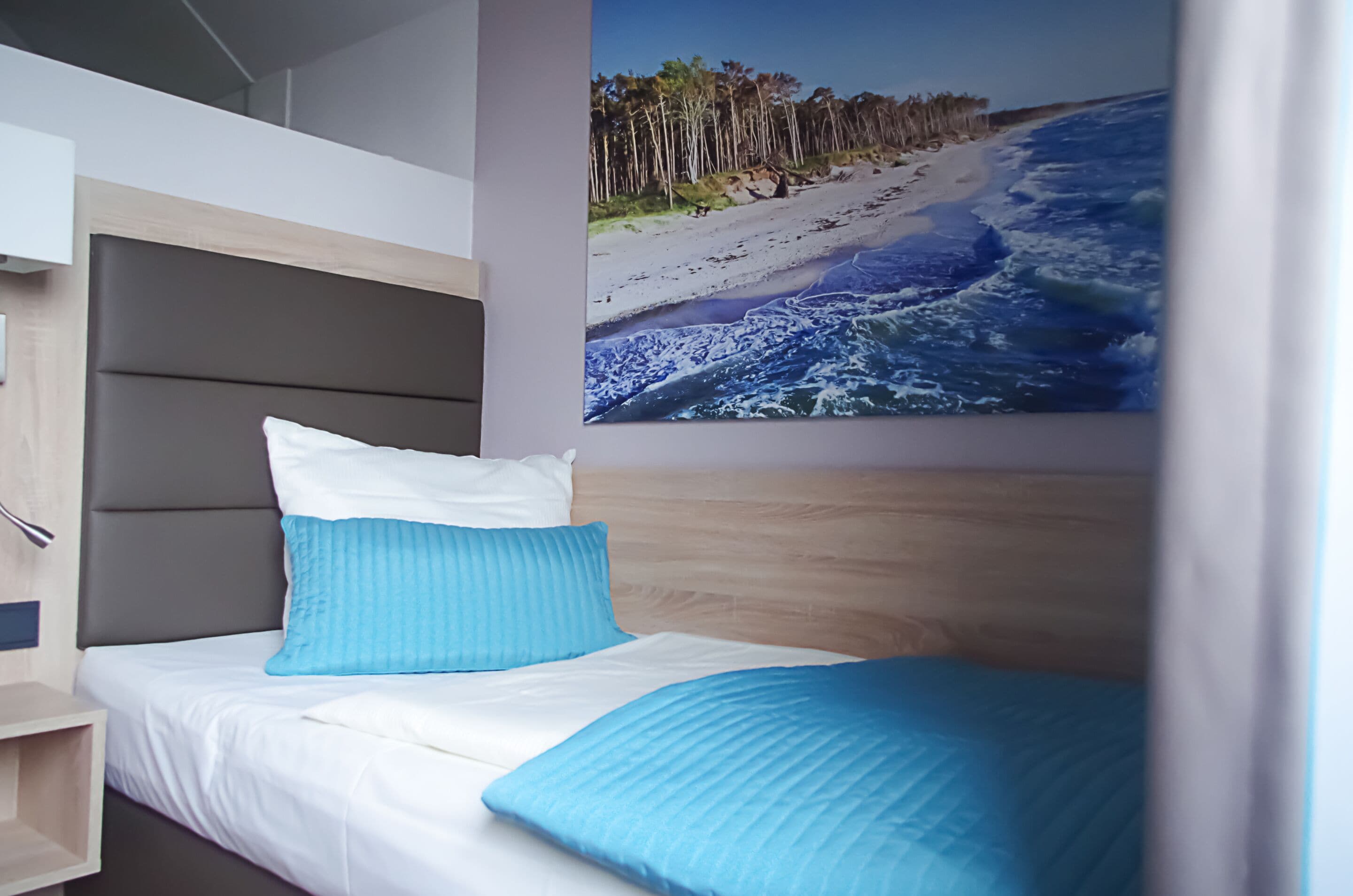 Ein Schlafzimmer mit Etagenbett, einem Einzelbett und einem großen Wandbild zum Thema Strand.