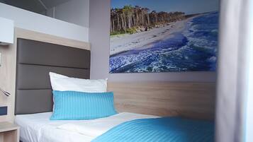Ein Schlafzimmer mit Etagenbett, einem Einzelbett und einem großen Wandbild zum Thema Strand.