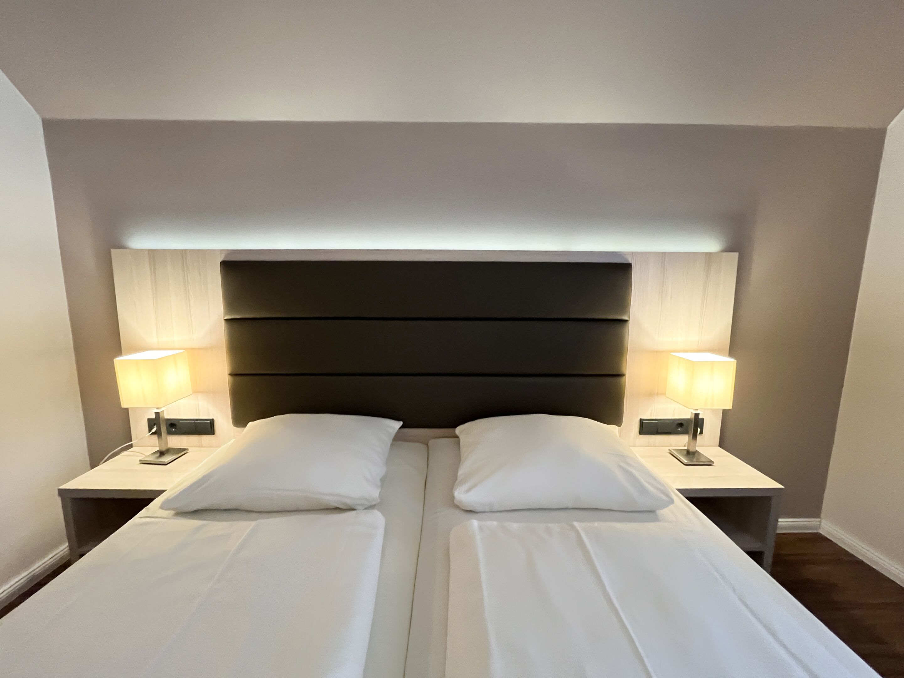A double bed with a dark headboard and two bedside tables with lamps.