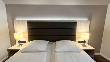 A double bed with a dark headboard and two bedside tables with lamps.