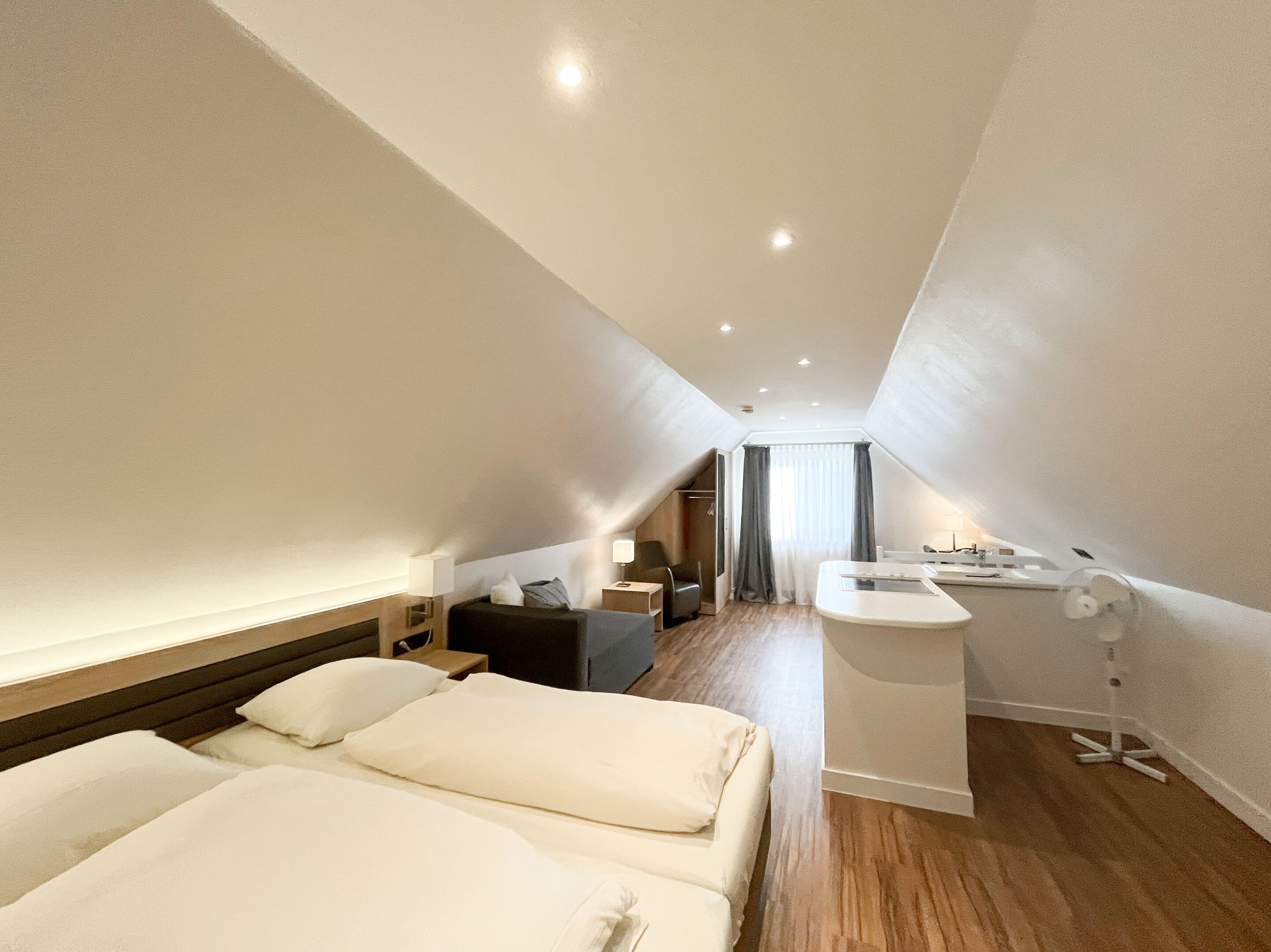 Une chambre d’hôtel moderne avec un grand lit, un bureau et une petite kitchenette.