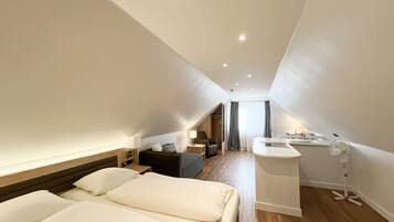 Une chambre d’hôtel moderne avec un grand lit, un bureau et une petite kitchenette.