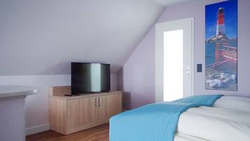 A bedroom with a bed, a TV on a wooden cabinet, and a painting of a lighthouse on the wall.