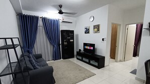 Una sala de estar con un sofá negro, un televisor sobre un mueble negro, un ventilador de techo y un reloj en la pared.