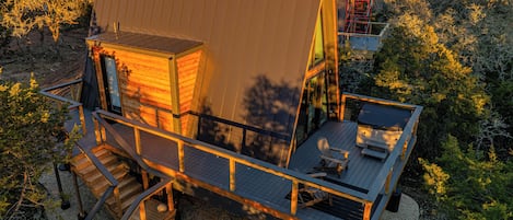 Une cabane moderne en bois dotée d’une grande terrasse, d’un bain à remous et d’un escalier menant à l’entrée principale.
