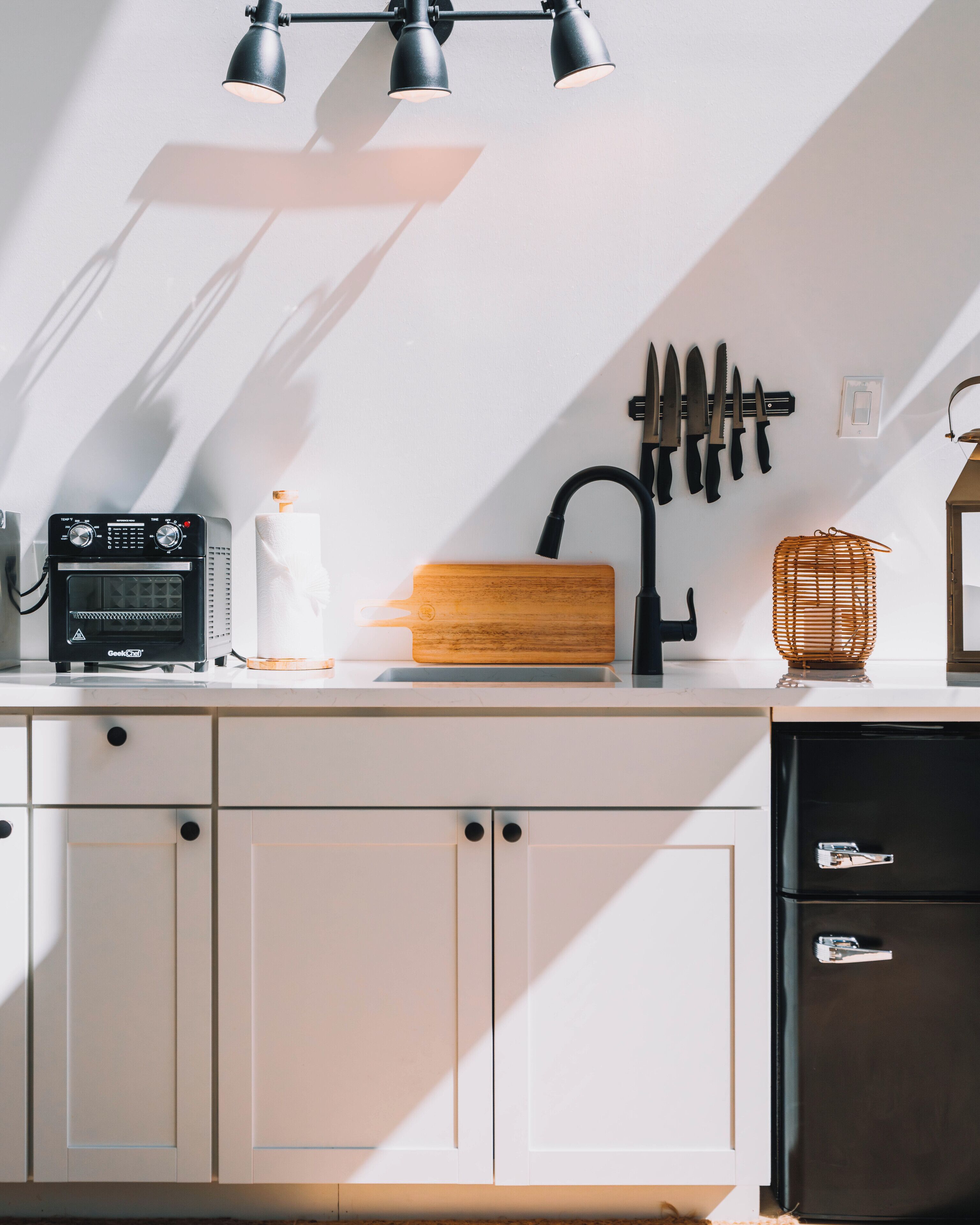 A kitchen with a built-in oven, a wooden cutting board, a sink, and a knife rack.