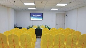 Un salón de conferencias con sillas amarillas, una pantalla de proyector y una puerta.