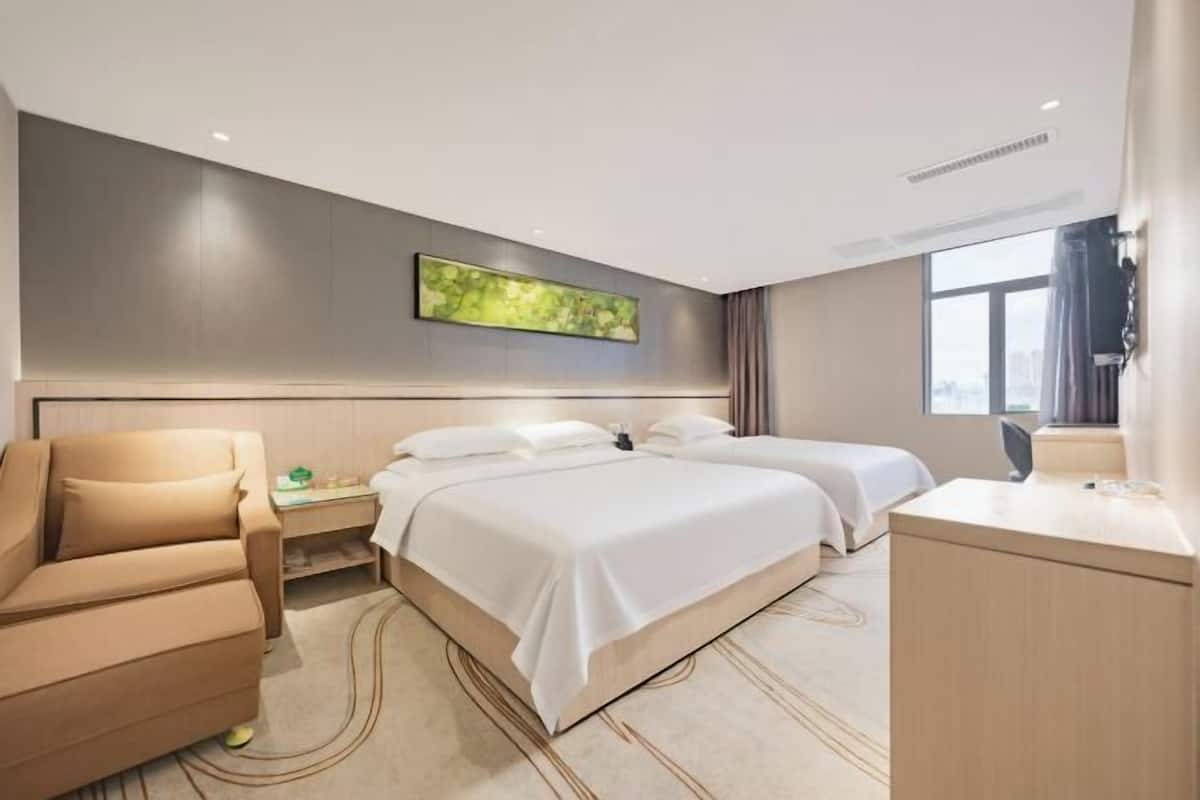 Una camera d'albergo moderna con un letto, un divano, una scrivania e un'ampia finestra.