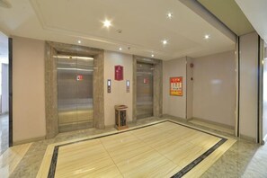 An elevator area with two elevators, a small table, and a polished floor. - Gold and Silver Business Hotel Huaiji (Huaiji)