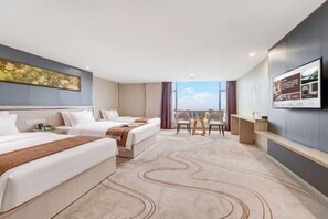 Ein Hotelzimmer mit zwei Betten, einem Schreibtisch, einem Stuhl und einem großen Fenster mit Blick.