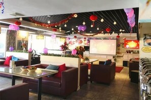 Un hall de hotel con zonas de estar, una pantalla grande y decoración festiva.