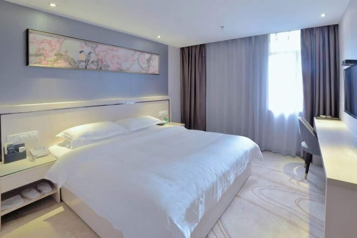Una camera d'albergo moderna con un grande letto, una scrivania e una televisione.