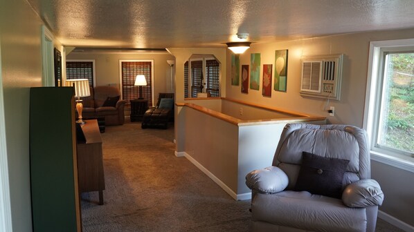 A cozy living room with a high ceiling, a staircase, and a view of the outdoors.