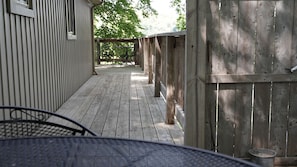 A wooden deck with a metal railing, a metal table, and a metal chair.