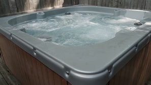 A hot tub with a wooden exterior and a control panel on the side.