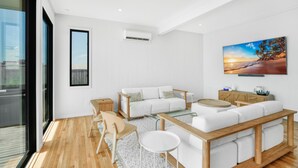 Ein modernes Wohnzimmer mit einem weißen Sofa, einem Couchtisch und einem an der Wand montierten Fernseher.