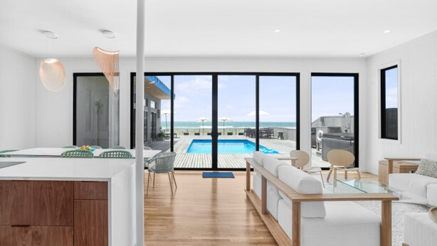 Ein modernes Hotelzimmer mit Holzboden, Pool und Blick auf den Strand.