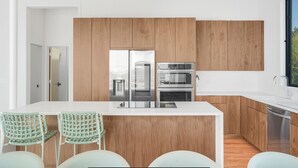 Eine moderne Küche mit Holzschränken, Edelstahlgeräten und einer weißen Arbeitsplatte.
