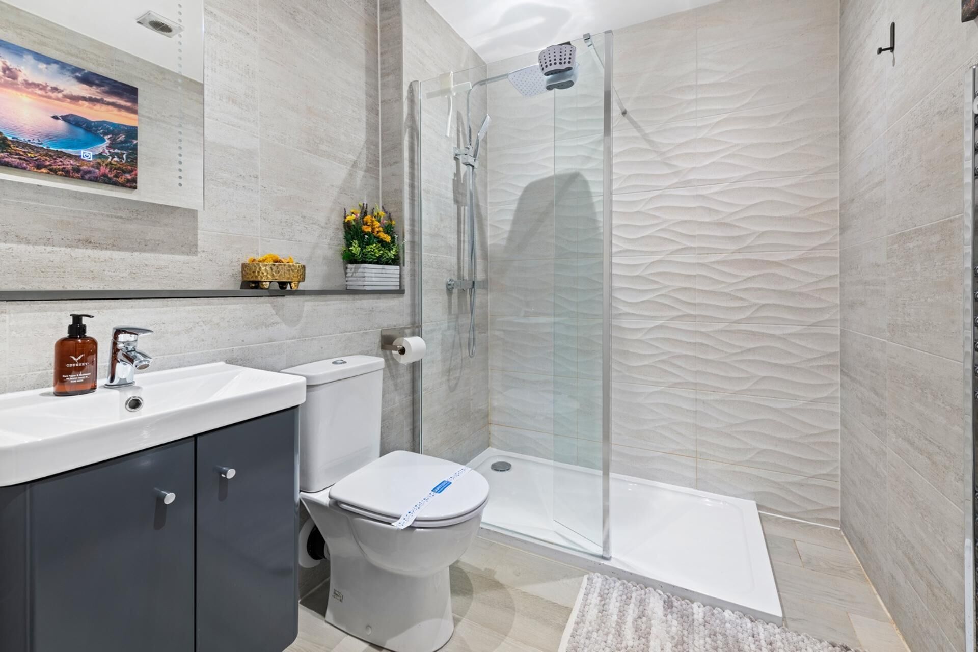 Une salle de bain moderne avec une douche à parois de verre, des toilettes et un lavabo avec un miroir au-dessus.