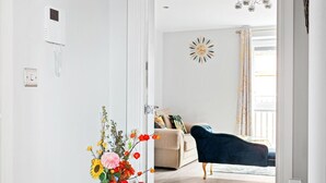 Un salon moderne avec un canapé beige, un fauteuil bleu et une horloge murale décorative.